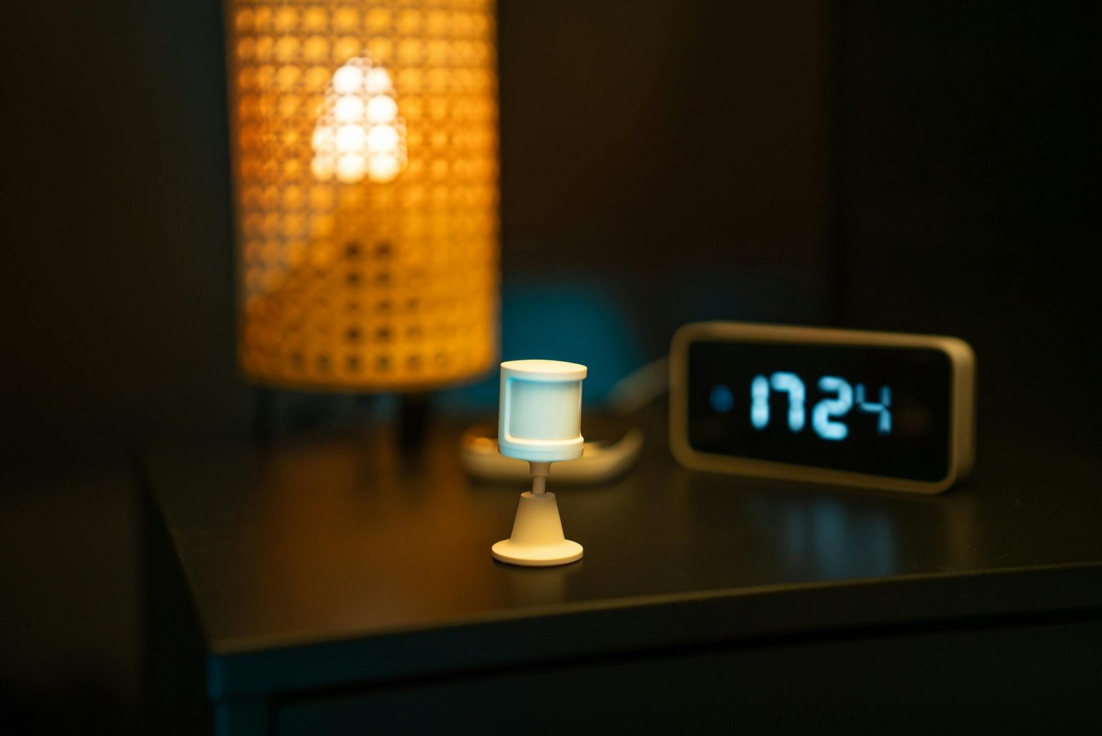 A smart home nightstand featuring a motion sensor, digital clock, and warm-toned lamp, creating a cozy ambiance.